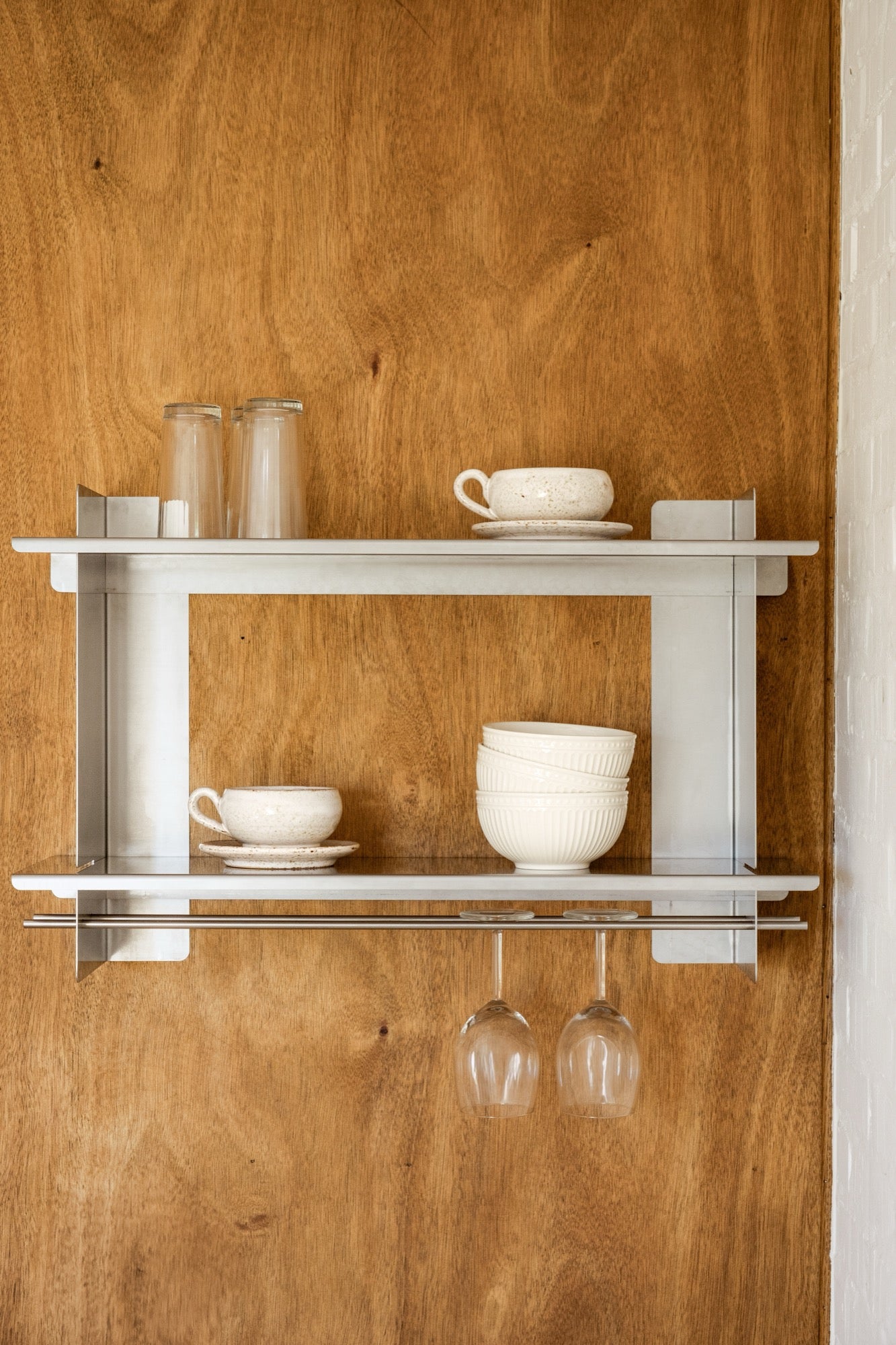 the Tivo Shelf Short in stainless steel mounted on a wooden kitchen wall storing crockery