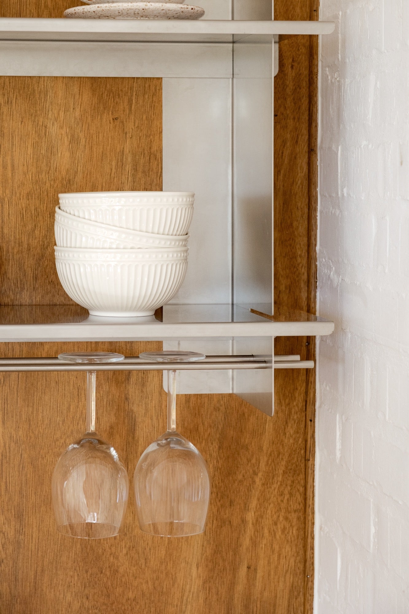 a close up of the Tivo Shelf Short in stainless steel mounted on a kitchen wall storing crockery and cutlery