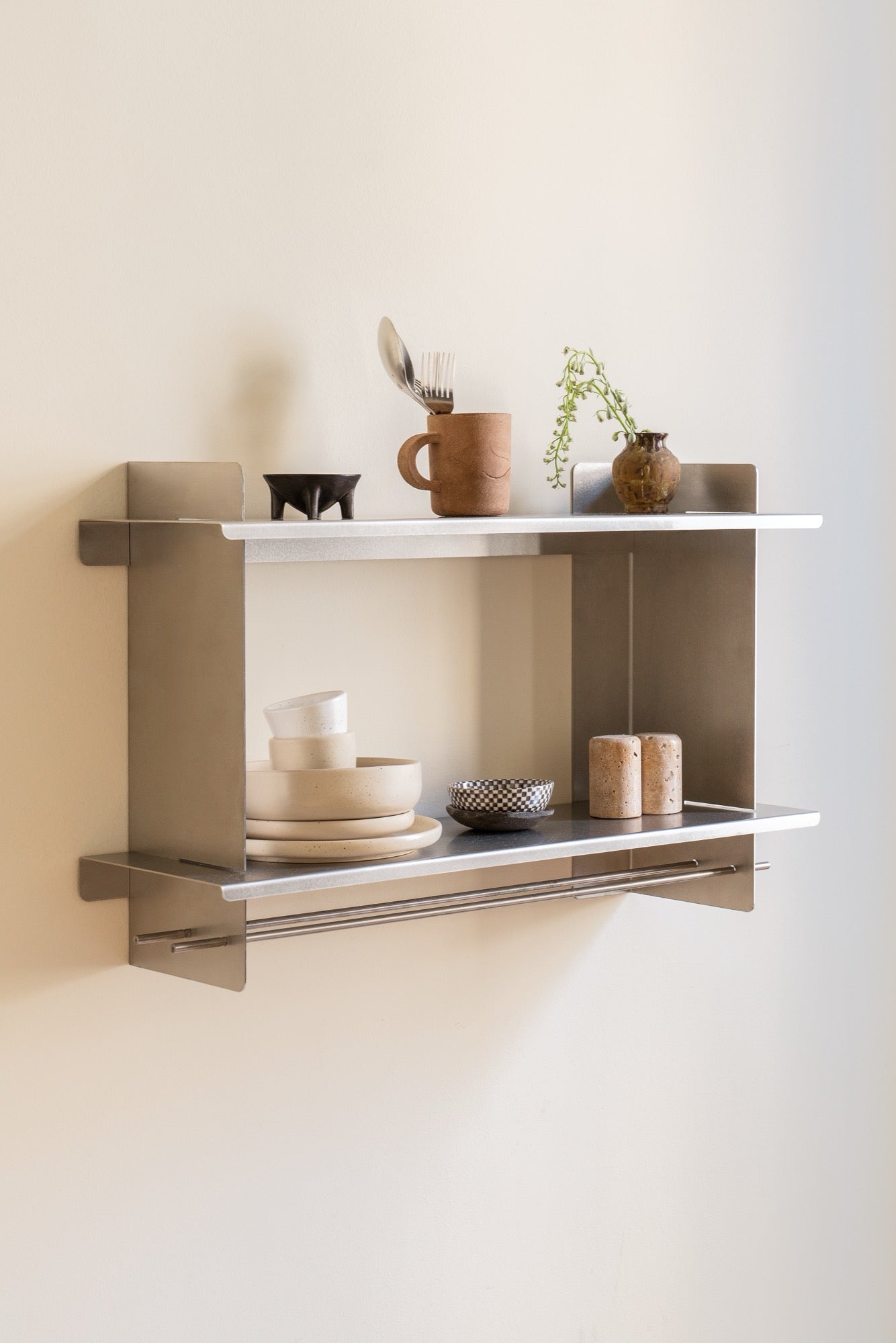 the Tivo Shelf Short in stainless steel mounted on a white kitchen wall storing crockery and cutlery
